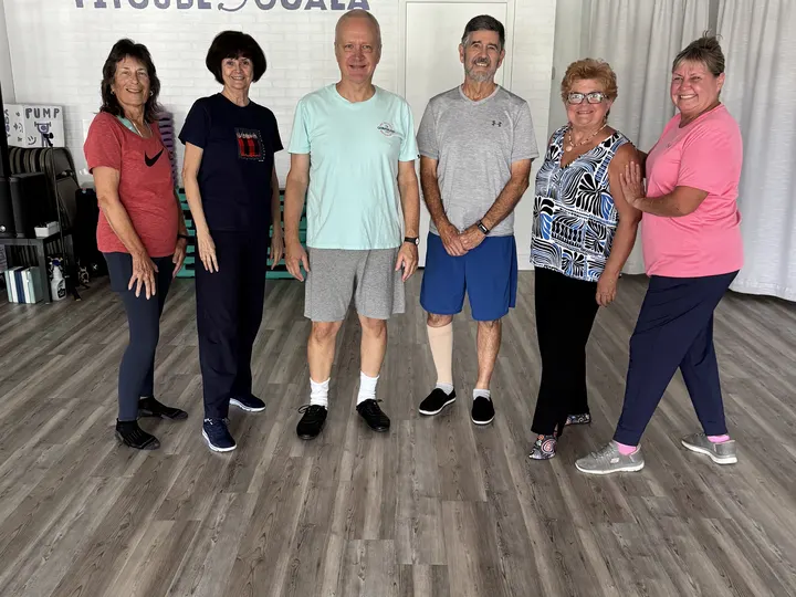Six members standing together in the studio after class