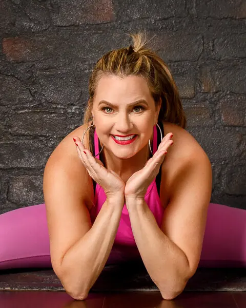 Lauren Taub smiling in a pink top, chin resting on her hands