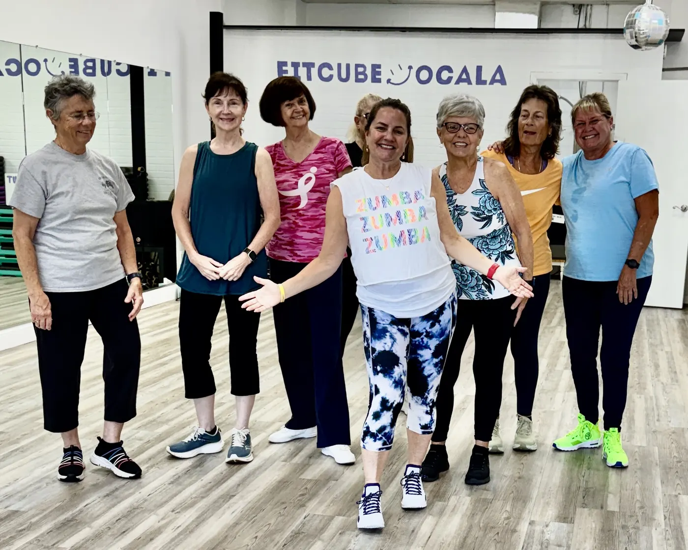 Eight FitCube members smiling together inside the studio under the FitCube Ocala sign