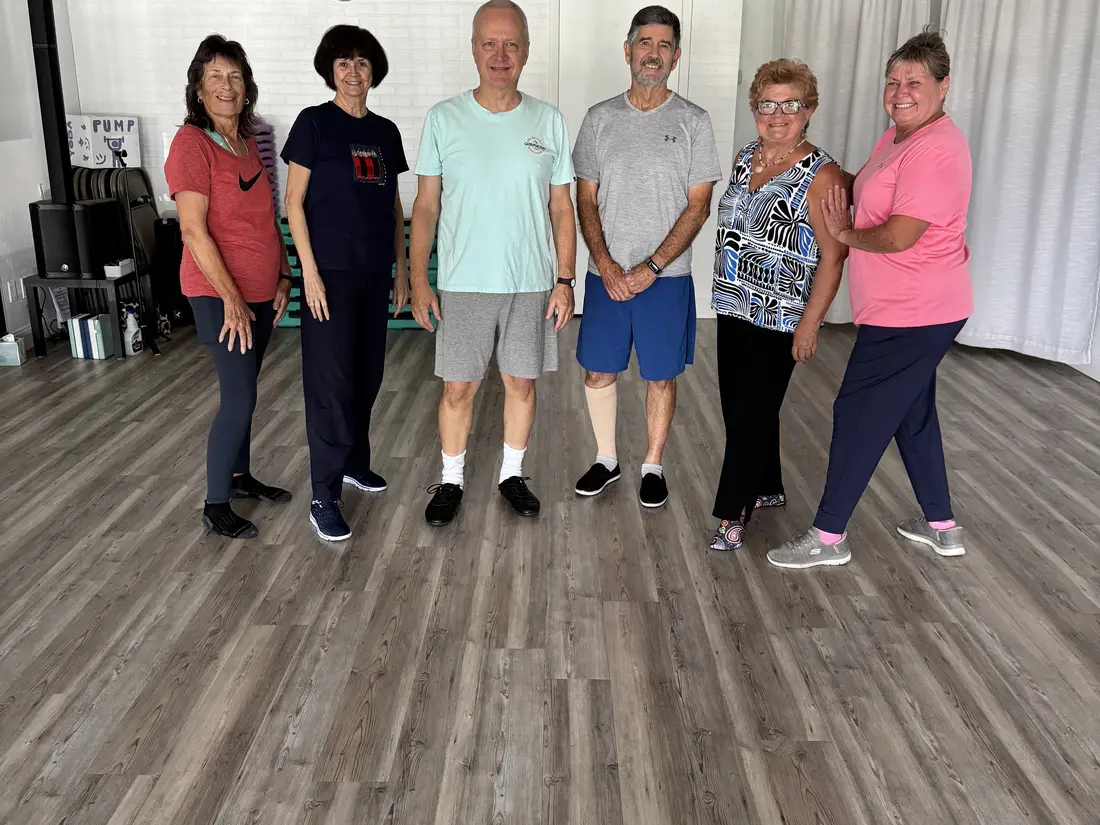 Seven FitCube members standing together in the studio under the FitCube Ocala sign