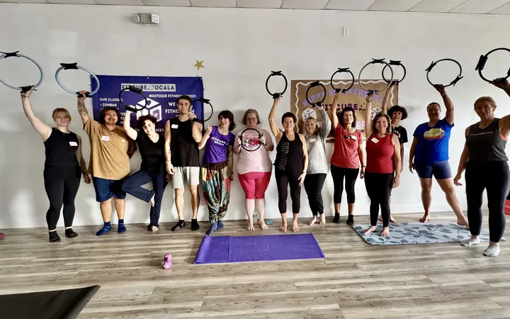 A Pilates class holding their rings overhead under the FitCube banner