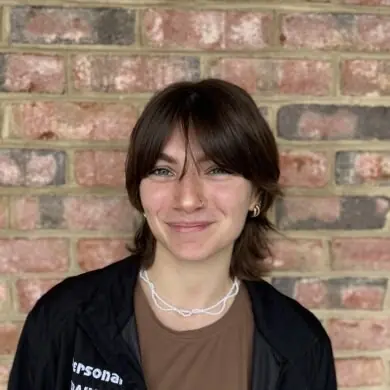 Ces Swinton smiling in front of a brick wall