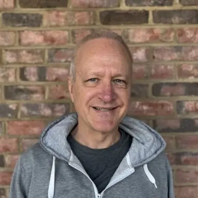 Edward Potter, who teaches Tai Chi, smiling in front of a brick wall