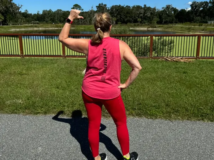 Lauren mid-strut on the park path, one arm raised