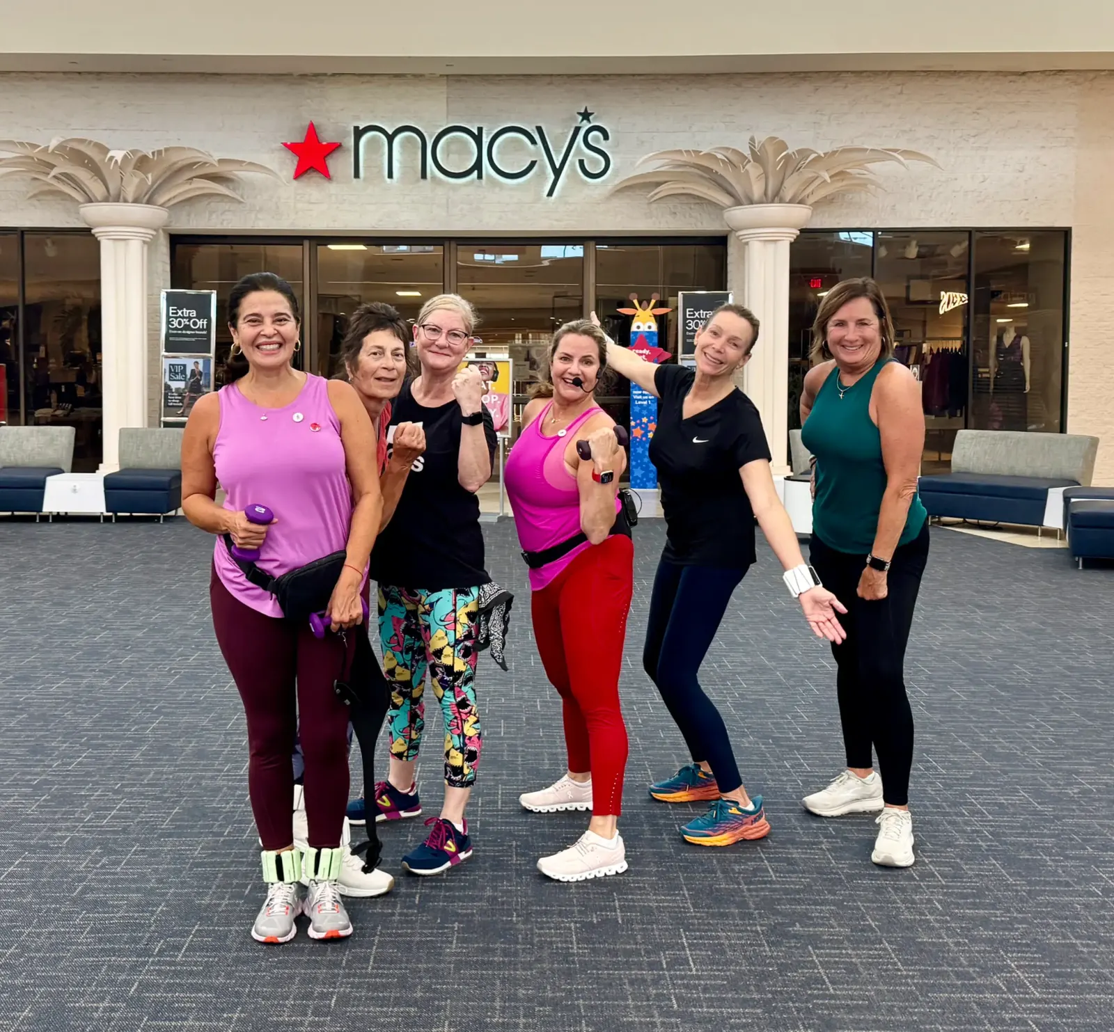 A Strutercize group smiling together after a walk, hand weights in hand